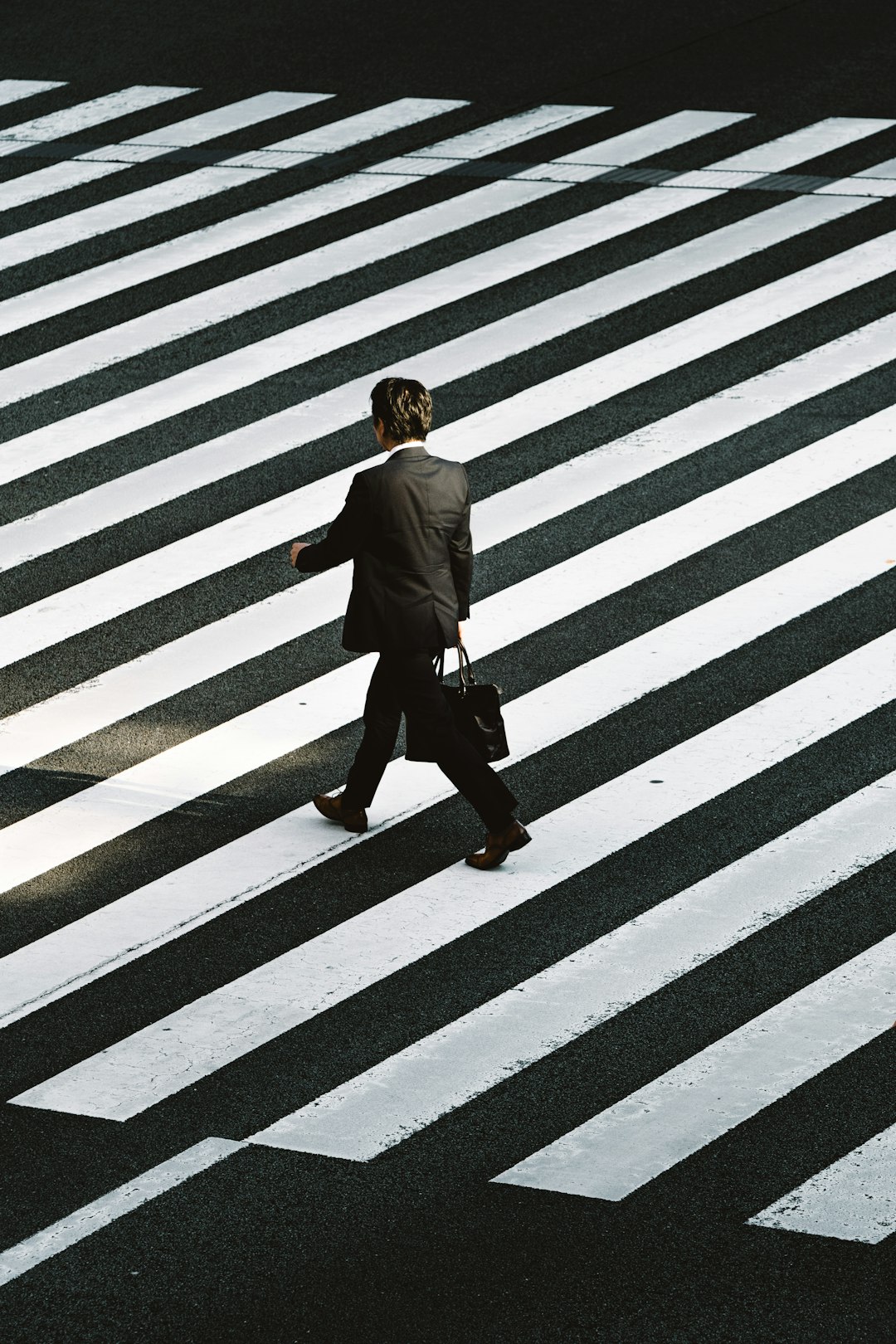 cta-bg man-in-black-formal-suit-jacket-and-pants-carrying-black-bag-while-walking-on-pedestrian-lane-during-daytime-wuzjnov7t0g